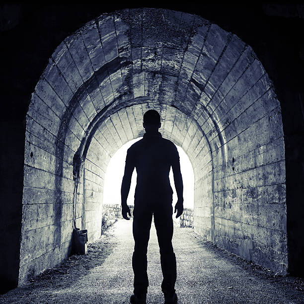 istock Young man stands in tunnel and looks on glowing end 515686237