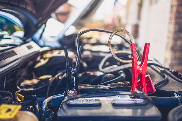Professional roadside technician support using an emergency jump start cable to connect a battery from other car to the one which out of battery.