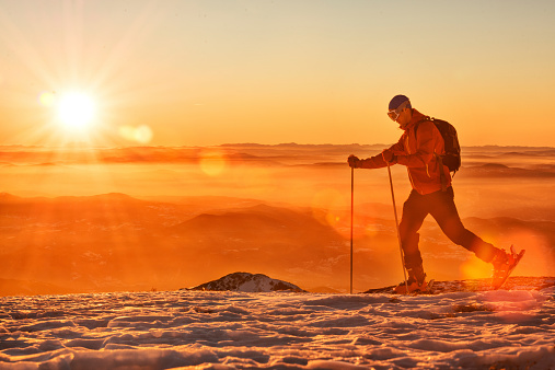 Sunset on the mountain and man walking on skis.