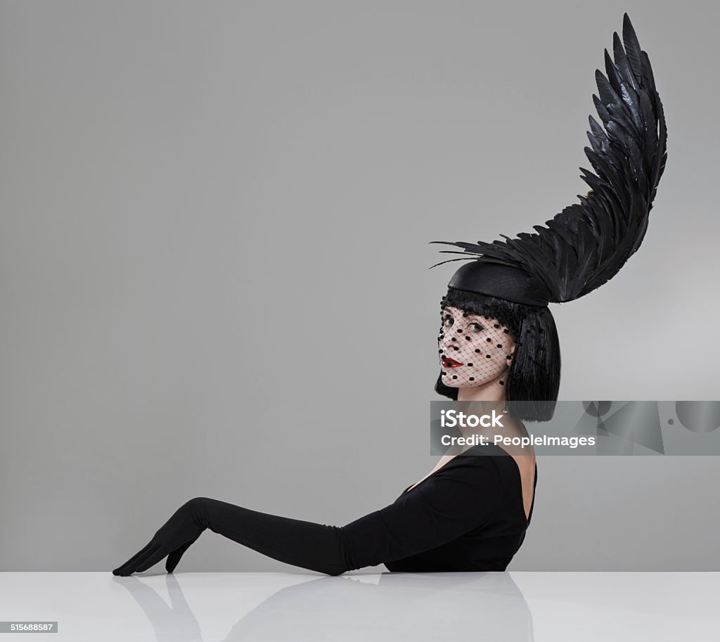 Just winging it Shot of a young woman in a wing-shaped headpiece sitting in a studio Abstract Stock Photo