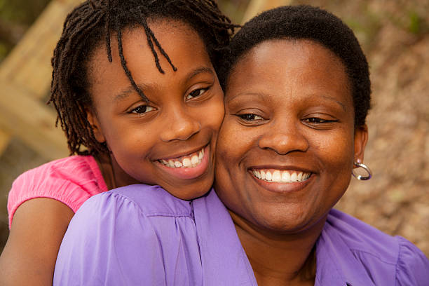 istock Relationships: African descent mother and daughter hug outside. 515690375