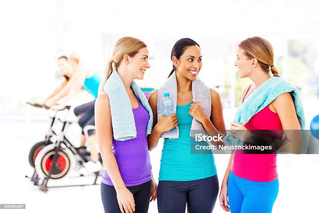 Fitness Class With Water Bottle And Towels In Health Club Beautiful female friends with water bottle and towels looking at each other in health club. Horizontal shot. 20-24 Years Stock Photo