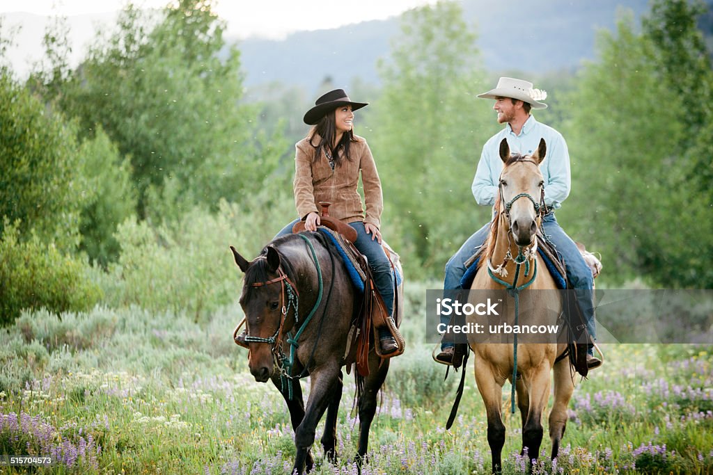 Rancher couple, Montana A young couple ride their horses through a heather valley, Parade Rest Ranch, Montana, USA.  Horseback Riding Stock Photo