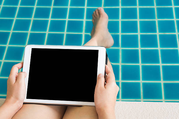 istock Woman working with  tablet sitting at swimming pool 515704633