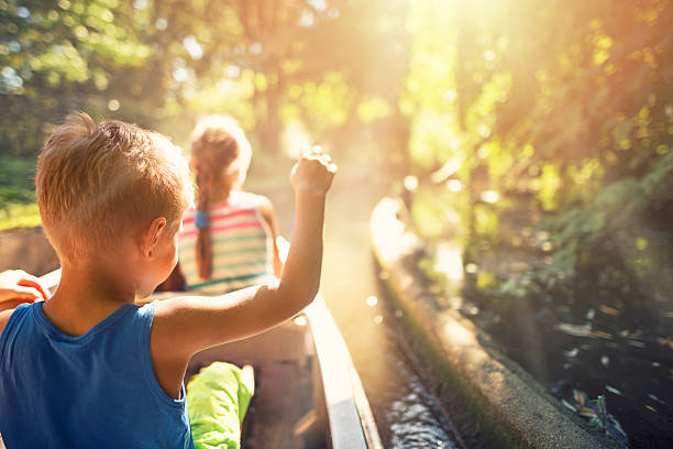 Kids enjoying ride in a boat through the forest river