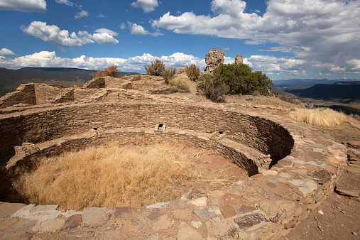 A 1000 year old Chacoan great house kiva remains at Chimney Rock National Monument where massive rock formations named Chimney rock and companion (on right) stand the distance and align with the solstice moon and the pueblos themselves.