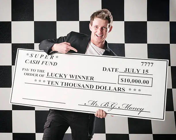 A smiling young man holding a large $10,000 check.