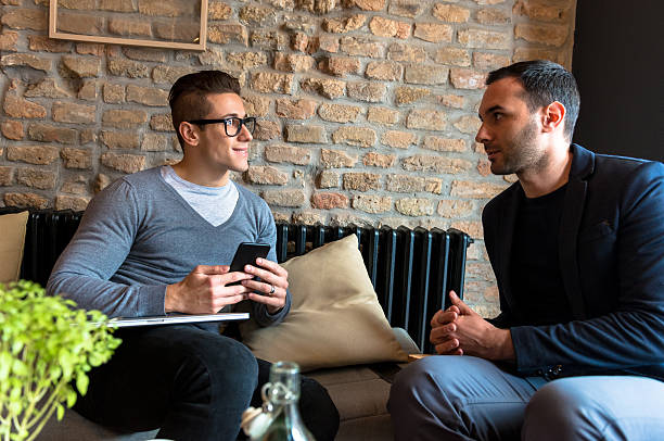 istock Two male friends sitting close and discussing in modern cafe 515708070