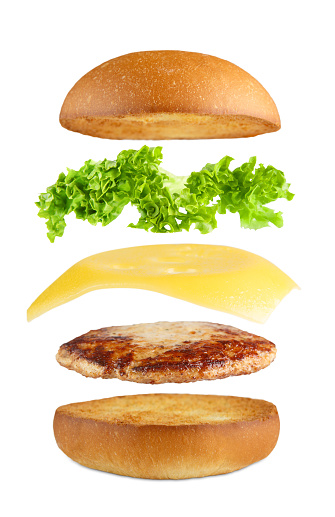 American food. Burger layers isolated. Separated burger layers isolated. Hamburger explosion. Cheeseburger flying fillings isolated at white background. Levitation of burger and cheese, meat, lettuce.