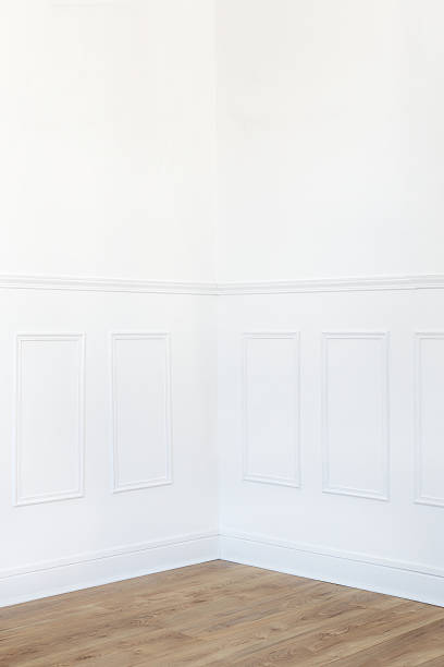 Empty white room interior corner with parquet floor and wood trimmed wall