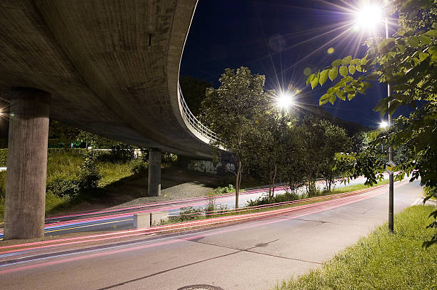 Cars passing under bridge and bright lights stock photo