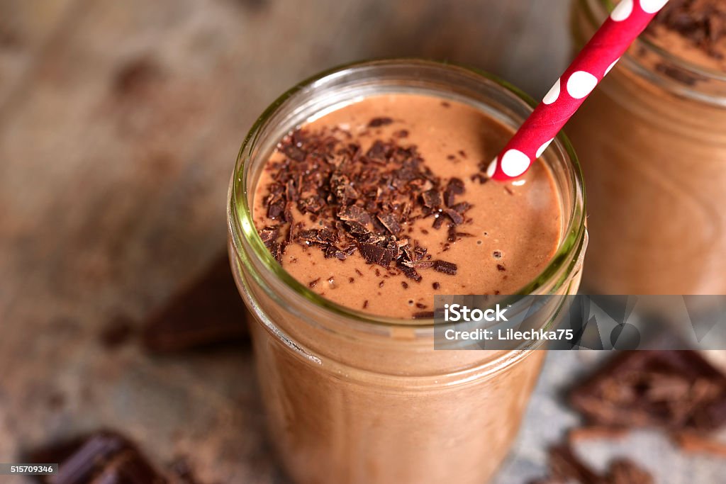 Chocolate babnana smoothie. Chocolate babnana smoothie on a rustic wooden background. Drinking Straw Stock Photo