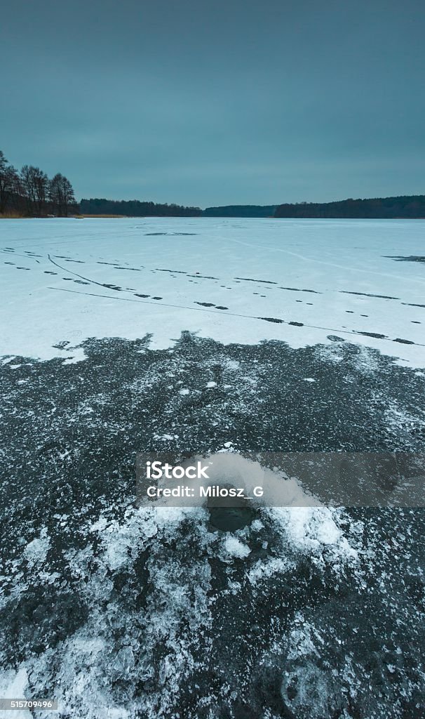 Frozen lake with hole in ice made by fisherman Frozen lake landscape with hole in ice for ice fishing. Beautiful lake in Poland. Arctic Stock Photo