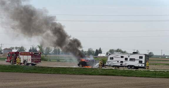 Atwood, Ontario, Canada - May 17, 2013: Fire fighters work to extingish the flames of a truck that started on fire while pulling a recreational vehicle travel trailer.
