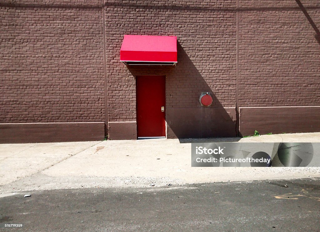 Side red brick building red door and red awning daytime Awning Stock Photo