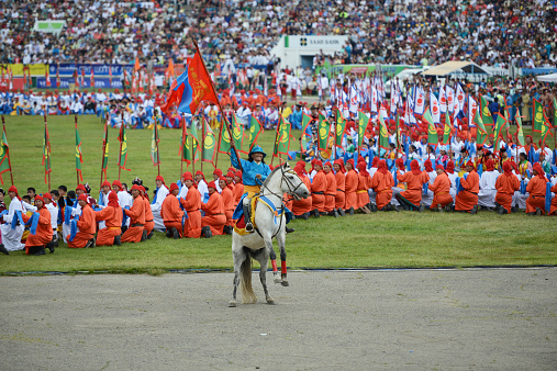 Ulan Bator, Mongolia- July 11, 2013 : A man riding a horse and greeting the audience with his Mongolian flag in his hand at Naadam Festival Opening Ceremony in Ulan Bator.