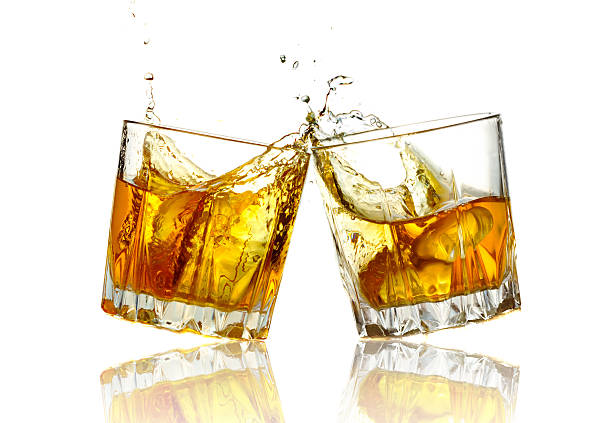 istock Two whiskey glasses clinking together, isolated 515725283