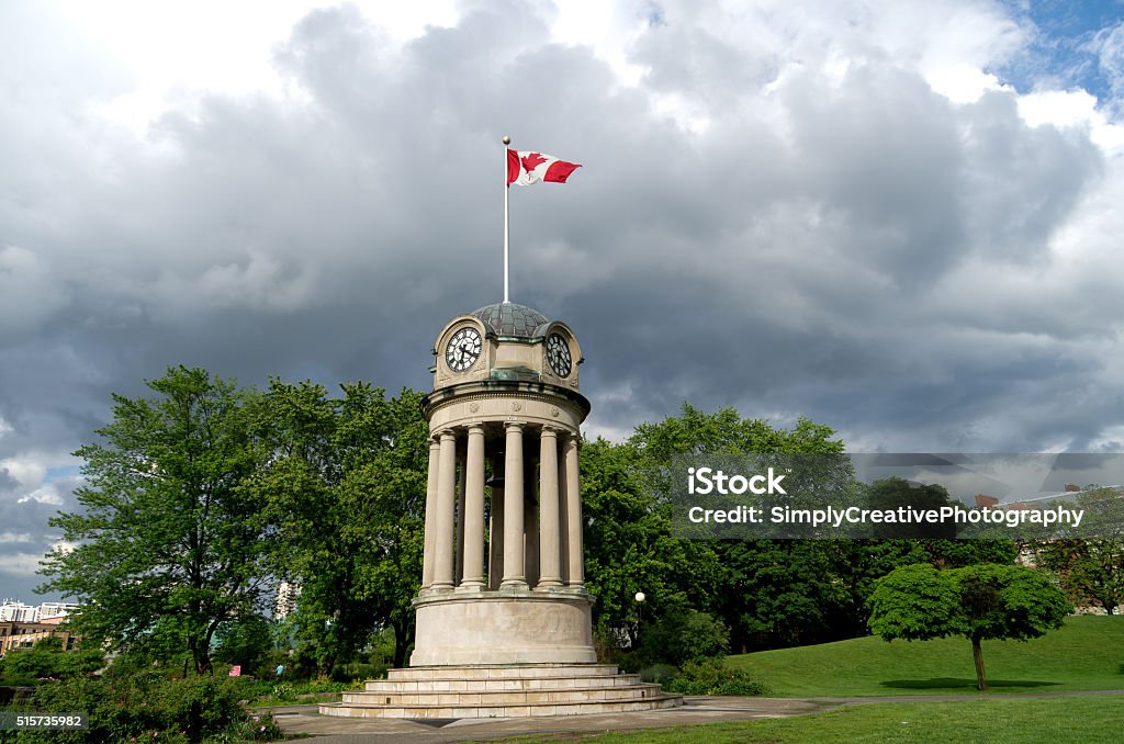 Canadian Flag on Clock Tower The clock tower in Kitchener's Victoria Park with the Canadian Flag against a dark storm clouds. Nice summer scene with sunlight illuminating clock tower for great contrast. Canada Stock Photo
