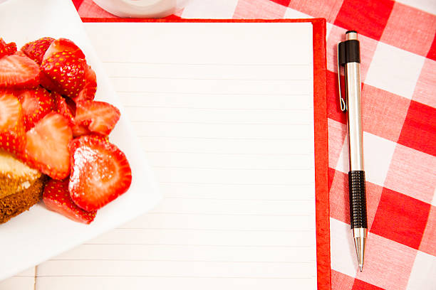 Fresh strawberry fruits on plate. Notepad, pen.