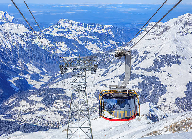 ""Rotair"" cable car gondola on Mt. Titlis Engelberg, Switzerland - 9 March, 2016: "Rotair" cable car gondola heading downwards, view from the station on the top of Mt. Titlis. Rotair gondolas make a 360 degrees turn during the five-minute trip. Titlis is a mountain of the Uri Alps, located on the border between the cantons of Obwalden and Bern.  engelberg photos stock pictures, royalty-free photos & images