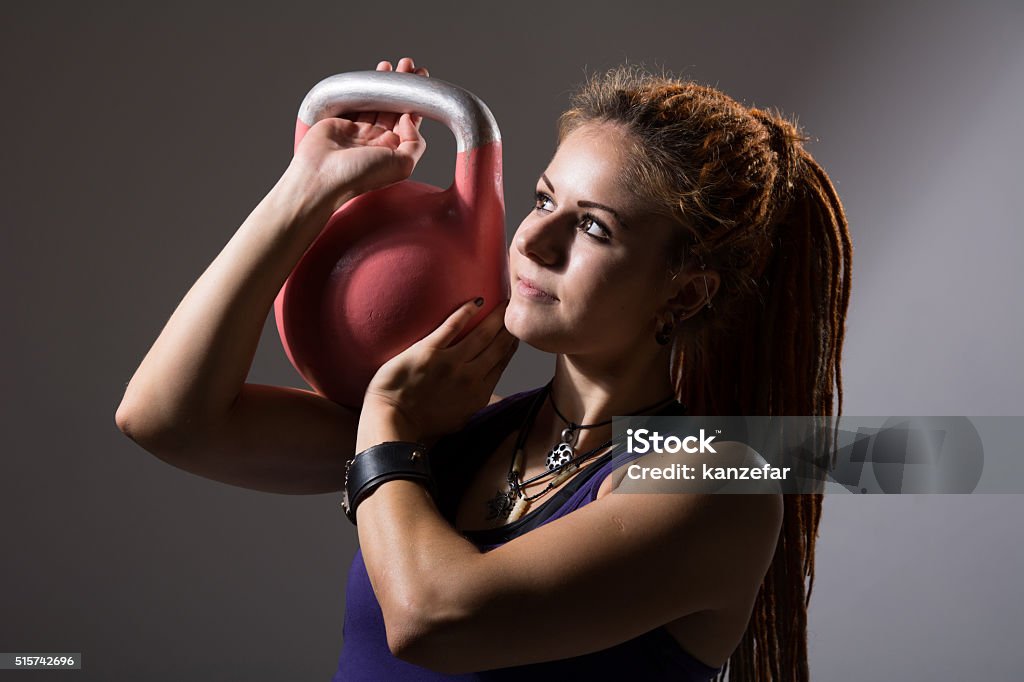 Portrait close up of young attractive female Portrait close up of young attractive female doing kettle bell exercise on grey background. Fitness woman working out. gym exercise. Adult Stock Photo