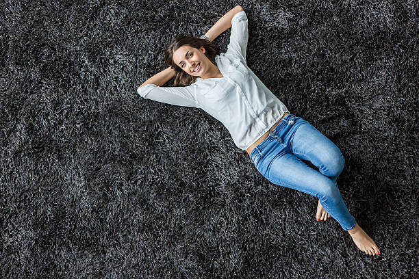 jovem mulher colocar no carpete - lying on the floor - fotografias e filmes do acervo