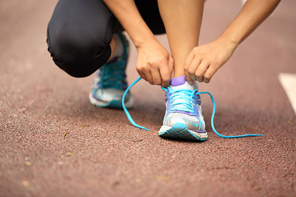 istock woman runner  tying shoelaces on trail 515743775