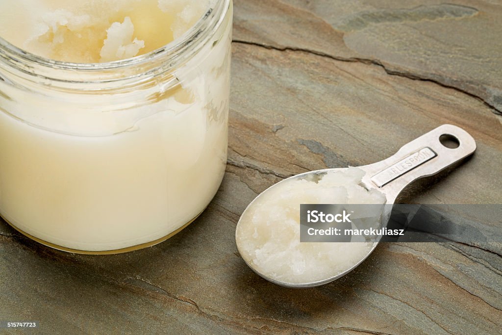 coconut cooking oil measuring tablespoon and glass jar coconut cooking oil on a slate rock background Coconut Oil Stock Photo