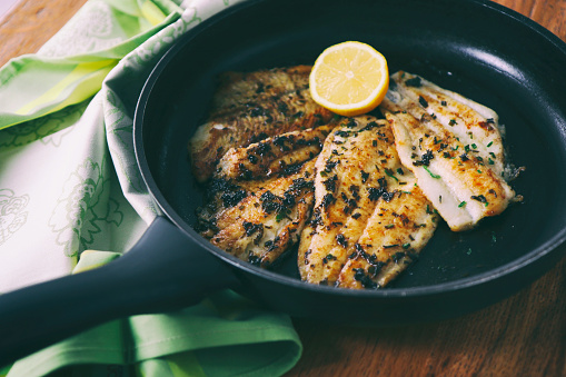 Flounder fillet roasted in a skillet with herbs and lemon butter 