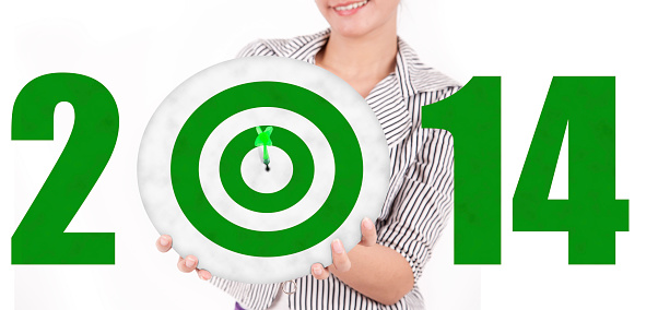 Smiling businesswoman showing green dartboard with number of 2014