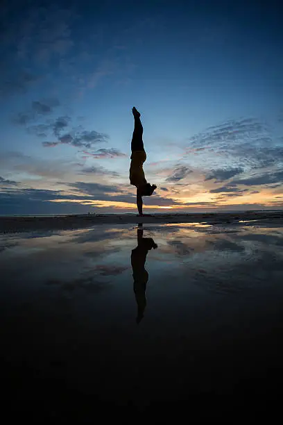 Photo of girl doing handstand on beach in sunset