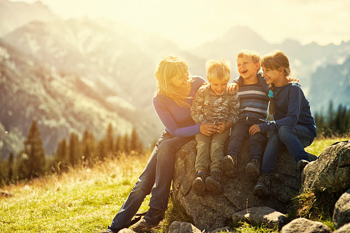 Mother and three kids hiking in mountains.