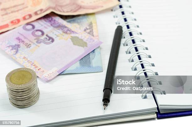 Coin With Money Thailand And Pen On Notebook Stock Photo - Download Image Now - Adult, Bank - Financial Building, Banking