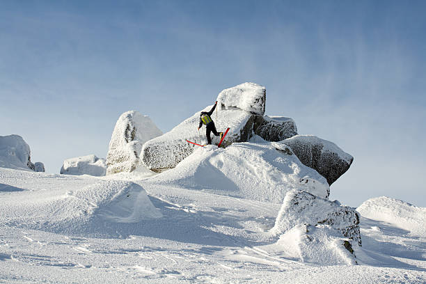 Back country skier crossing a rocky terrain during a mountain trip in a beautiful winter day with a new snow cover.