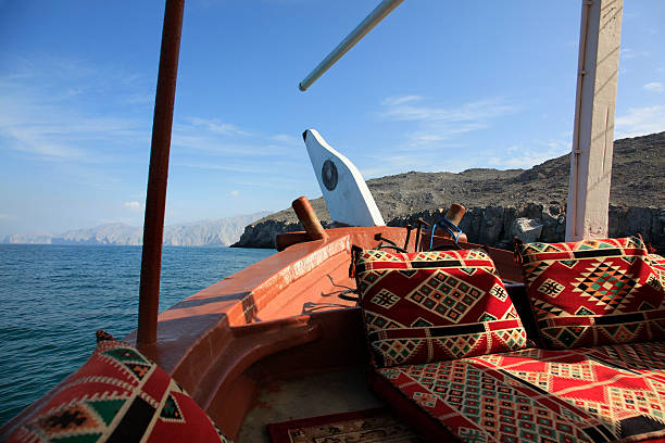 Dhow in front of the Musandam coast, Oman Cruising on a Dhow (traditional boat) in Musandam Fjords from Khasab, Oman dhow photos stock pictures, royalty-free photos & images