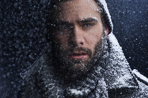 Cropped shot of a serious young man covered in snow in the dark