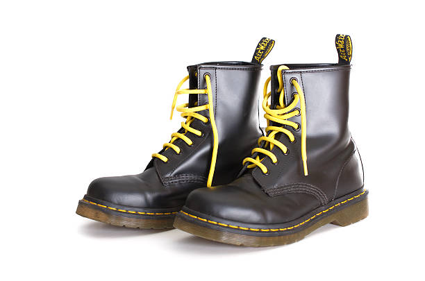 Classic black Doc Martens lace-up boots with yellow laces Tel Aviv, Israel - September 28, 2014: A pair of Doc Martens 8 eyelet 8 inch classic unisex black lace-up fashion combat boots with yellow laces and the sole visible lace up stock pictures, royalty-free photos & images