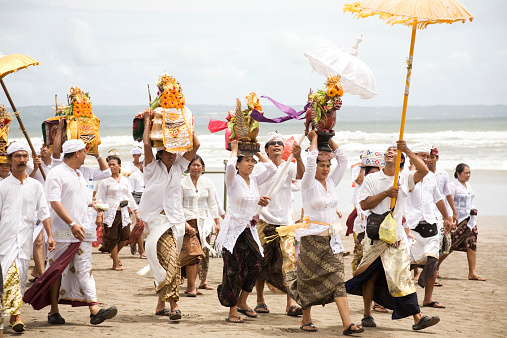 Bali, Indonesia - March 02, 2011: a procession of people сarrying religious offerings on the Seminyak beach for Melasti festival in Bali
