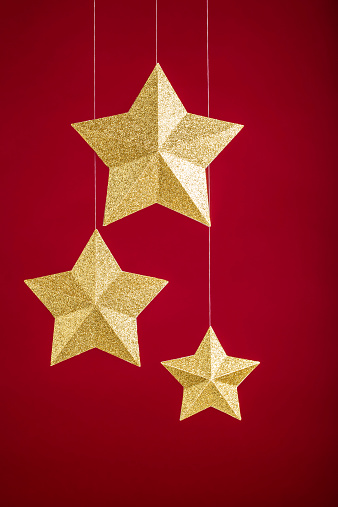 Three gold stars hanging over a red background.