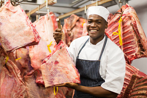 african butcher handing beef in slaughterhouse smiling african butcher handing beef in slaughterhouse african butcher holding meat stock pictures, royalty-free photos & images