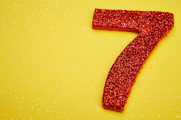 istock Number seven red color over a yellow background. Anniversary 515801994
