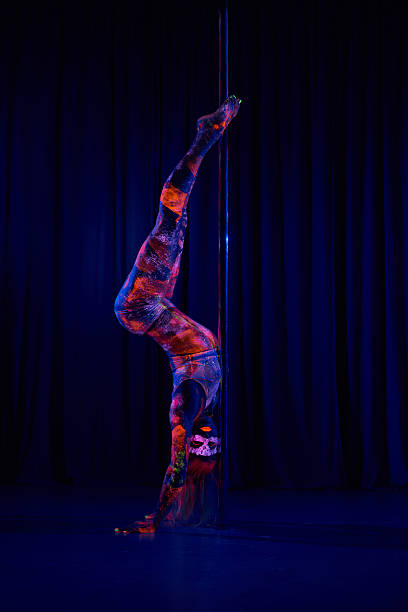 Female pole dancer in neon colours under ultraviolet (UV) light Female pole dancer in bright neon colours under ultraviolet (UV) light on background black pole dancers stock pictures, royalty-free photos & images