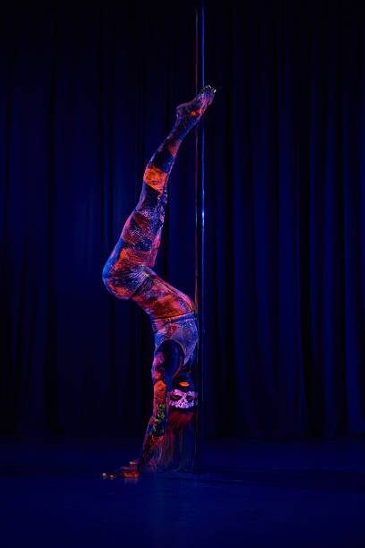 женщина танцовщица у шеста в неоновых цветах в ультрафиолетового (уф) излучения света - pole vibrant color dancer exercising стоковые фото и изображения