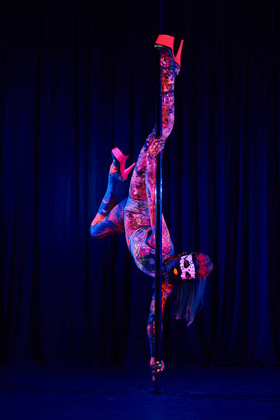 Female pole dancer in neon colours under ultraviolet (UV) light Female pole dancer in bright neon colours under ultraviolet (UV) light on background black pole dancers stock pictures, royalty-free photos & images
