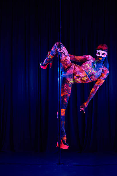 Female pole dancer in neon colours under ultraviolet (UV) light Female pole dancer in bright neon colours under ultraviolet (UV) light on background black pole dancers stock pictures, royalty-free photos & images