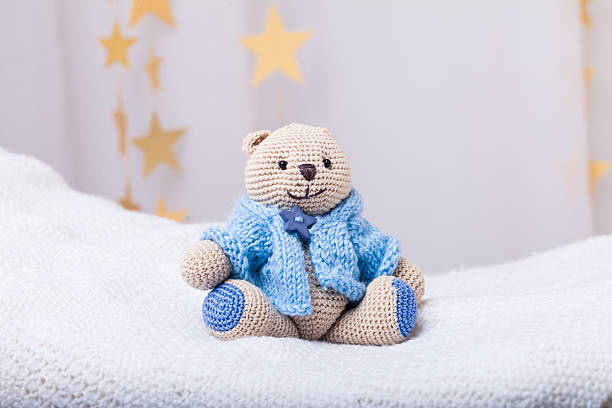 istock beige crocheted bear dressed on blue sweater on light background 515803344