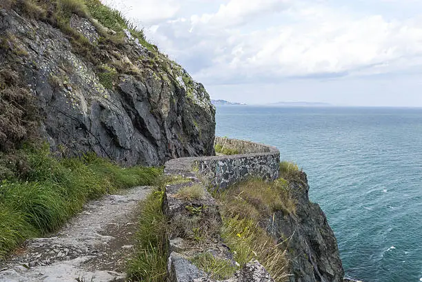 Photo of Stone rocks mountain hiking path at Irish seacoast. Bray, Greystone