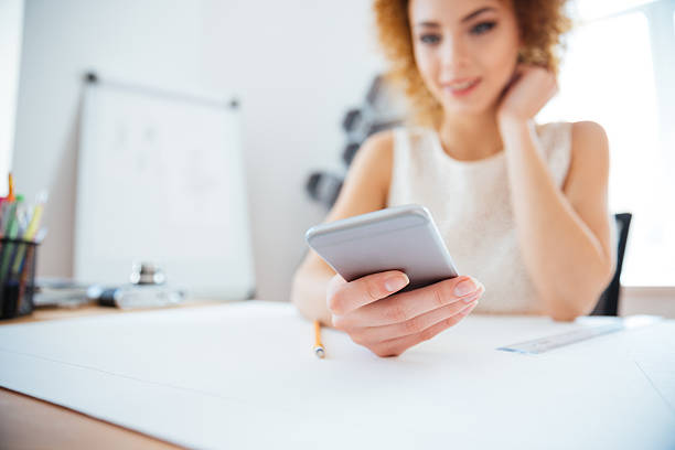 istock Attractive curly redhead businesswoman sitting and using smartphone 515806502