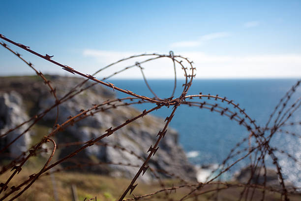 istock Barbed wire on fence with Atlantic ocean 515809127