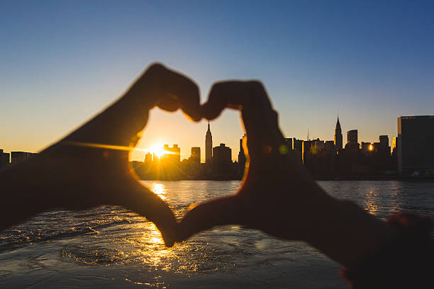 istock Heart Shaped Hands at Sunset, New York Skyline on Background 515809231